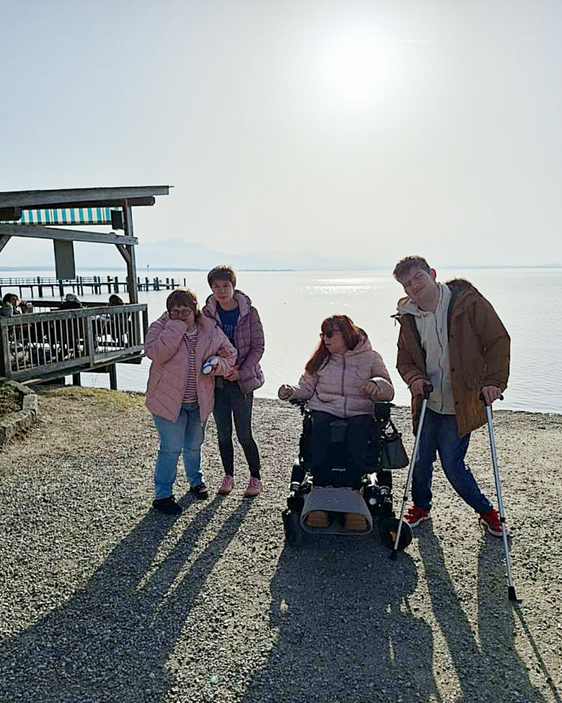 Vier Mitglieder der WG mit Herz vor dem Chiemsee am Strand